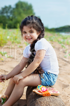 Laughing little girl posing sitting on log