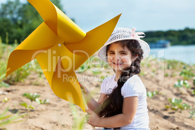 Cheerful dark-haired girl playing with windmill