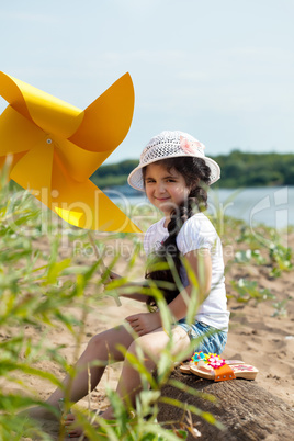 Pretty little girl posing with windmill in park