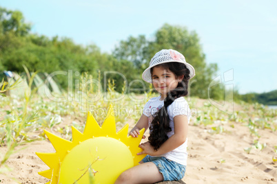 Playful young girl posing with paper sun