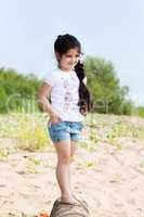 Smiling little girl posing walking along shore