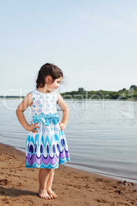 Little girl posing in smart dress on lake backdrop