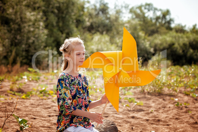 Thoughtful girl posing with paper windmill