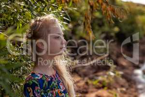 Profile of dreamy young girl posing with tree