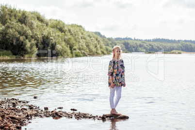 Pretty young girl posing barefoot on shore of Lake