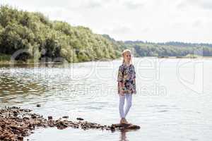 Pretty young girl posing barefoot on shore of Lake