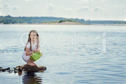 Cute girl preparing to launch paper boat at lake