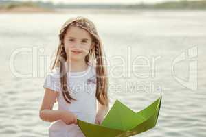 Sweet little girl posing with paper boat, close-up