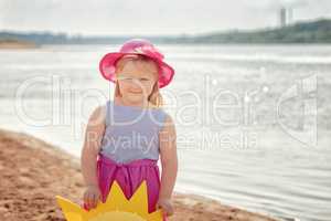 Smiling blond girl posing on river bank, close-up