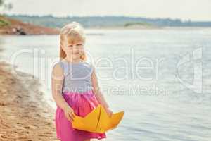 Nice blonde girl posing with homemade paper boat
