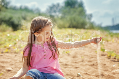 Cute little girl playing with sand in park