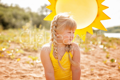 Tanned little blonde posing on sun background