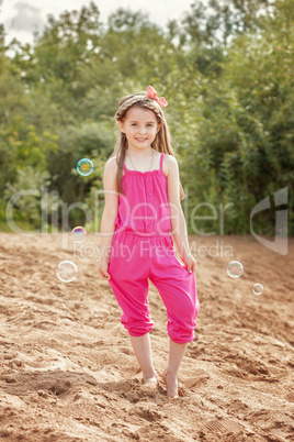 Cute little model posing in pink overall at beach