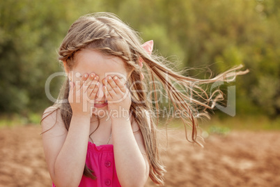 Cute little girl playing hide and seek with camera
