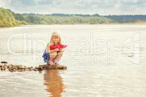 Cute little girl wants to run paper boat in lake