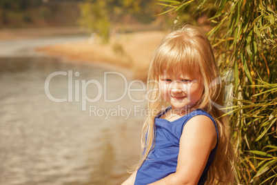 Portrait of little blond girl on vacation in park