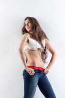 Seductive young model posing in unbuttoned jeans