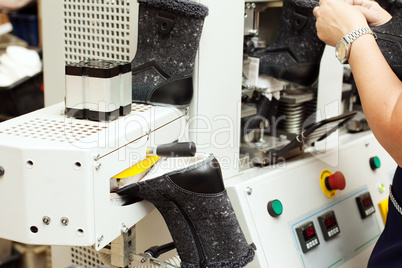 Worker adjusts machine for production of footwear
