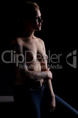 Topless tattooed woman posing in studio