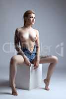 Image of tattooed model posing topless in studio