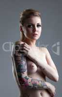 Naked tattooed woman with pierced nipples