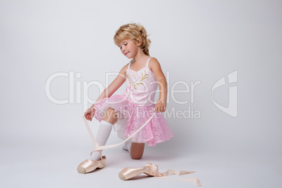 Amazing little ballerina tying pointes in studio