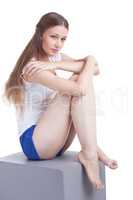 Sporty long-haired girl sitting on cube