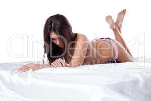 Studio shot of beautiful slim model lying in bed