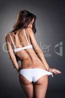 Rear view of slim tanned girl in white lingerie