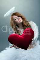 Cute girl in angel costume posing with teddy heart