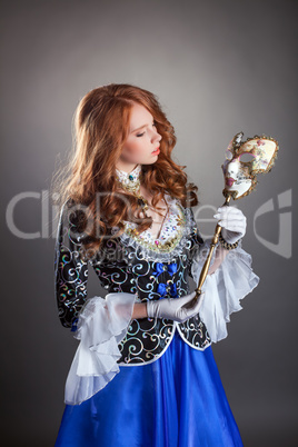 Lovely red-haired girl posing with masquerade mask