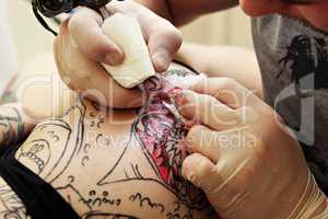 Master tattooing on girl's thigh, close-up