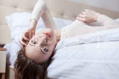 Portrait of seductive young woman lying on bed