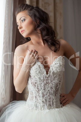 Sensual bride looking dreamily at window