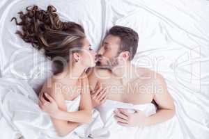 Beautiful lovers kissing while lying in bed