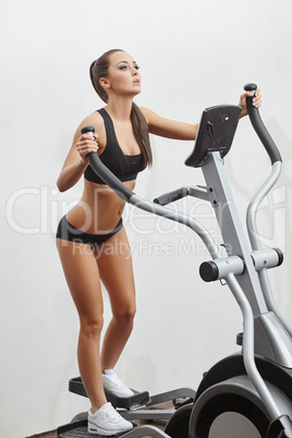 Sexy young sportswoman exercising on simulator