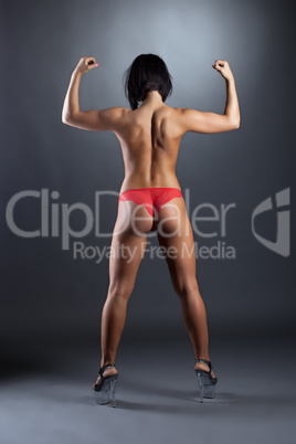 Rear view of tanned female dancer shows biceps