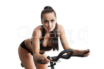 Sexy female athlete exercising on stationary bike
