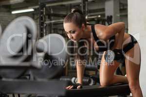 Exciting brunette exercising with dumbbells in gym