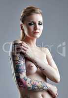 Tattooed naked woman with pierced nipple