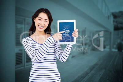 Composite image of cheerful woman pointing at tablet computer