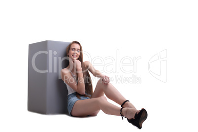 Smiling young girl sits leaning against cube