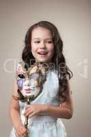Cheerful little girl posing with carnival mask