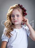 Image of cute girl tries on cherries as earring