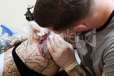 Close-up of tattooist draws on girl's hip