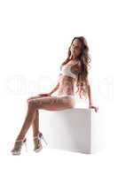 Beddable lingerie model posing sitting on cube