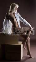Beautiful naked girl posing sitting on wooden box
