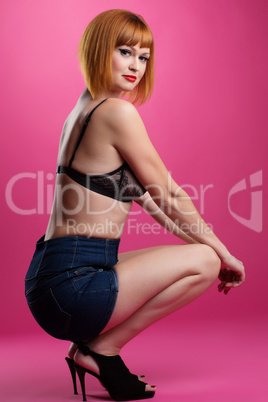 Slim redhead model posing on pink background