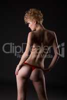 Rear view of slender woman dressed in red thong