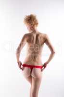 Rear view of topless blonde dressed in red thong